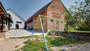 Ein Backsteinhaus mit geneigtem Dach, einer Schaukel und einer Terrasse mit Whirlpool und Sitzgelegenheiten.