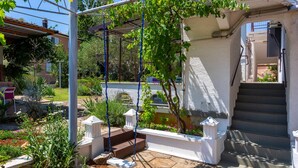 A garden with a swing set, steps leading to a door, and a staircase.