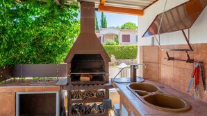 An outdoor kitchen with a wood-fired oven, a sink, and a barbecue grill.