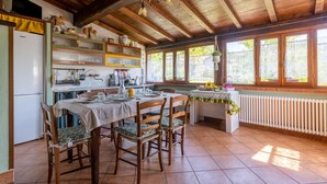 A rustic kitchen with wooden beams, a dining table set for four, and a view of greenery outside. - Gorgeous home in Fraz. Cogna, Piazza al (Fraz. Cogna, Piazza al)