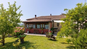 A traditional house with a tiled roof, stone walls, and a small garden with potted plants and a windmill. - Gorgeous home in Fraz. Cogna, Piazza al (Fraz. Cogna, Piazza al)