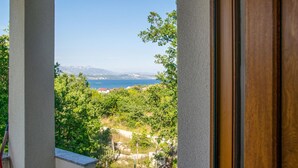 A view from a window overlooking a coastal landscape with trees and a clear sky. - Lovely home in Posedarje (Posedarje)