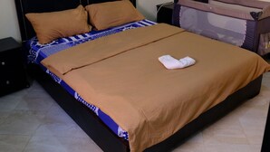 Ein Bett mit brauner Bettdecke, einem Kopfteil und einem Fußschemel.