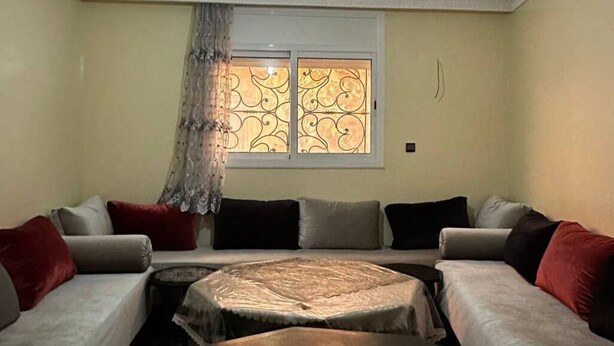 Ein Wohnzimmer mit einer Sofagarnitur, einem runden Couchtisch und einem Fenster mit dekorierter Scheibe.
