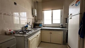 Eine Küche mit Gasherd, Schränken, einem Fenster und einem Kühlschrank.