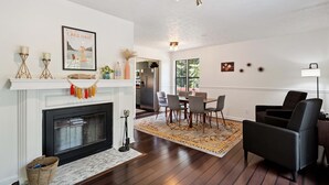 Una sala de estar con chimenea, comedor y una butaca de cuero negro.
