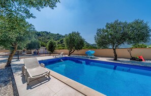 A swimming pool with lounge chairs, a children's play area, and a view of a hillside. - Stunning home in Ston (Ston)