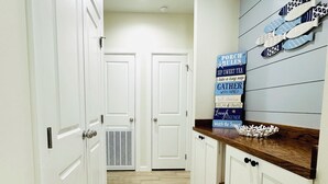 A narrow hallway with white doors, a wooden floor, and a kitchen area with a wooden countertop and decorative fish wall art. -  Just steps away from the beach, restaurants, stores, and carnival attraction.  (South Padre Island)