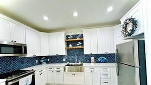 A modern kitchen with white cabinets, a stainless steel refrigerator, a microwave, and a stove. -  Just steps away from the beach, restaurants, stores, and carnival attraction.  (South Padre Island)