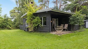 Eine kleine Hütte mit überdachter Veranda, zwei Stühlen und einem Tisch.