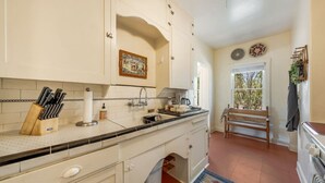 Een keuken met witte kastjes, een betegelde achterwand en een houten bank.