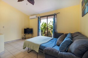 Relax in this serene space with a comfortable bed, a TV for entertainment, and a window with curtains for natural ambiance.