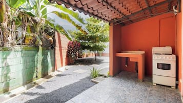 A covered outdoor area with a gas stove and oven, a table, and a green wall with plants.