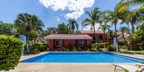 Relax by the pool surrounded by lush greenery and palm trees.