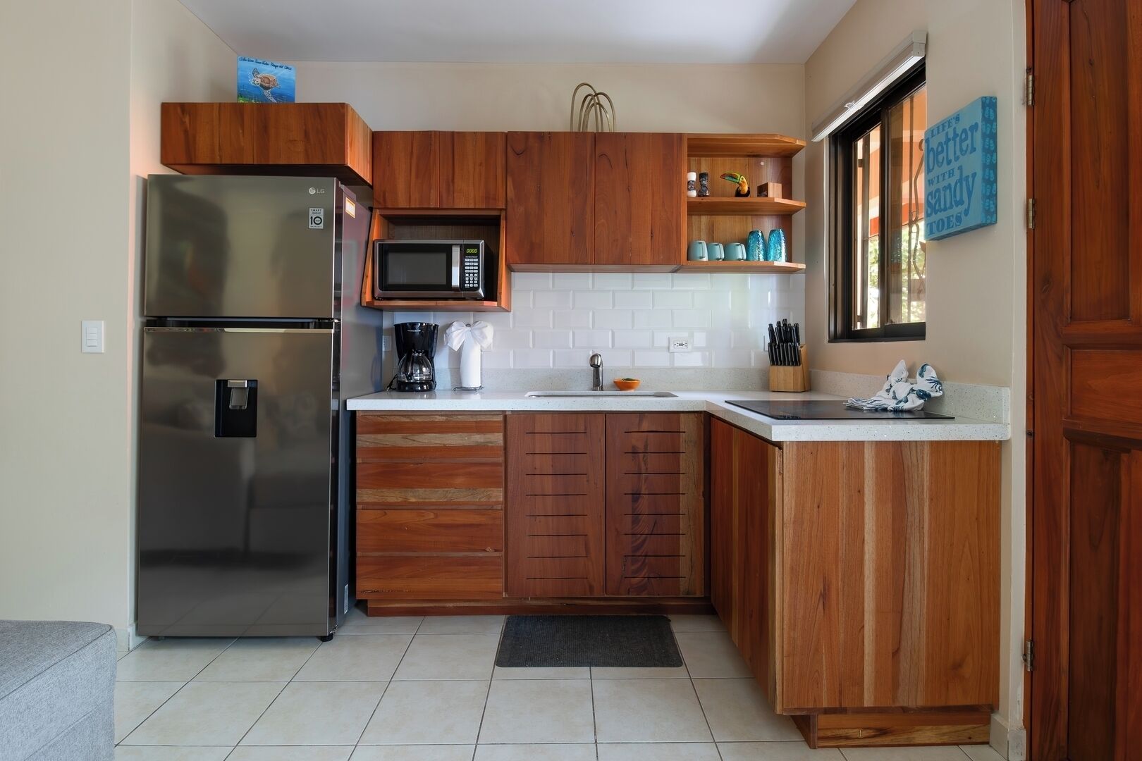 A kitchen with wooden cabinets, a stainless steel refrigerator, a microwave, and a coffee maker.