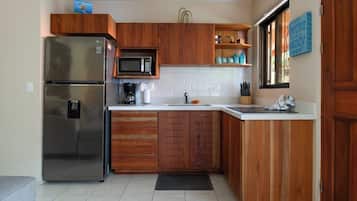 A kitchen with wooden cabinets, a stainless steel refrigerator, a microwave, and a coffee maker.