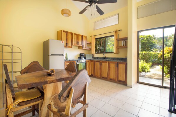 Enjoy cooking in this well-equipped kitchen with a central island and ceiling fan, adjacent to a balcony with a view of lush surroundings.