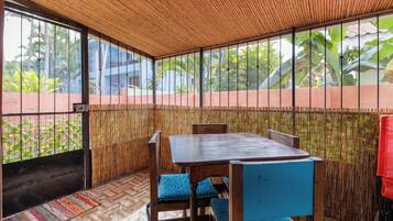 A room with a wooden ceiling, large windows, a bamboo wall, and a table with chairs.