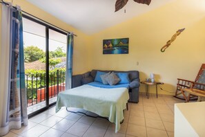 Relax in this cozy space with a comfortable bed, sofa, and balcony offering a peaceful retreat.