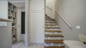 Un escalier orné de carreaux décoratifs et de marches en bois, menant à un palier avec une porte blanche.
