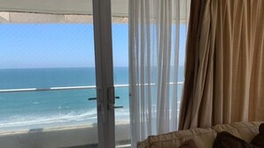 A room with a view of the ocean through a glass door, a beige sofa, and sheer curtains. - La Serena Avenida Del Mar 3 Bedrooms beach view  (La Serena)