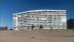A multi-story hotel with a curved facade, balconies, and a sandy beach in the foreground. - La Serena Avenida Del Mar 3 Bedrooms beach view  (La Serena)