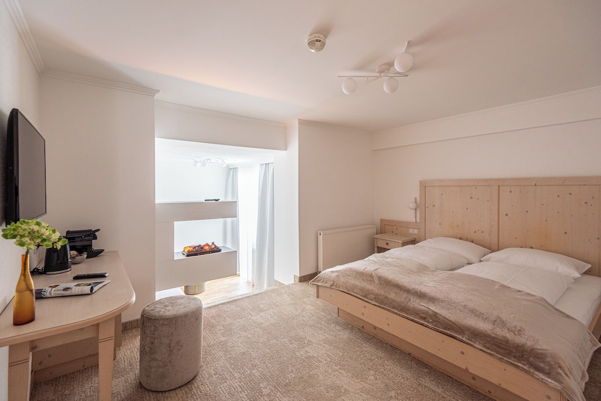 A bedroom with a wooden bed, a desk with a vase, and a radiator.