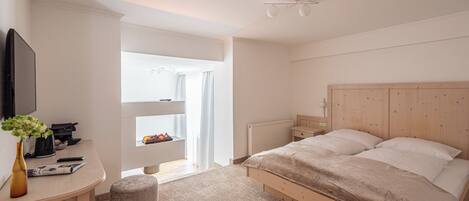 A bedroom with a wooden bed, a desk with a vase, and a radiator.