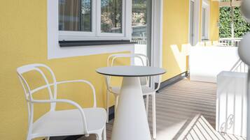 Eine Terrasse mit einer gelben Wand, weißen Stühlen und einem runden Tisch.