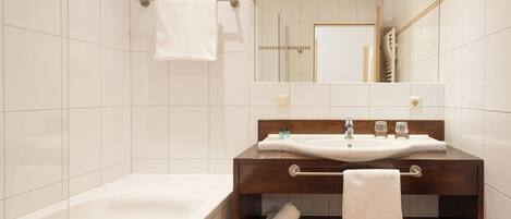 A modern bathroom with a bathtub, a wooden vanity with a sink, and a mirror.