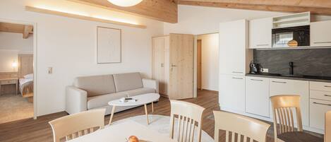 A modern kitchen with white cabinets, a wooden ceiling, and a dining area with a table and chairs.