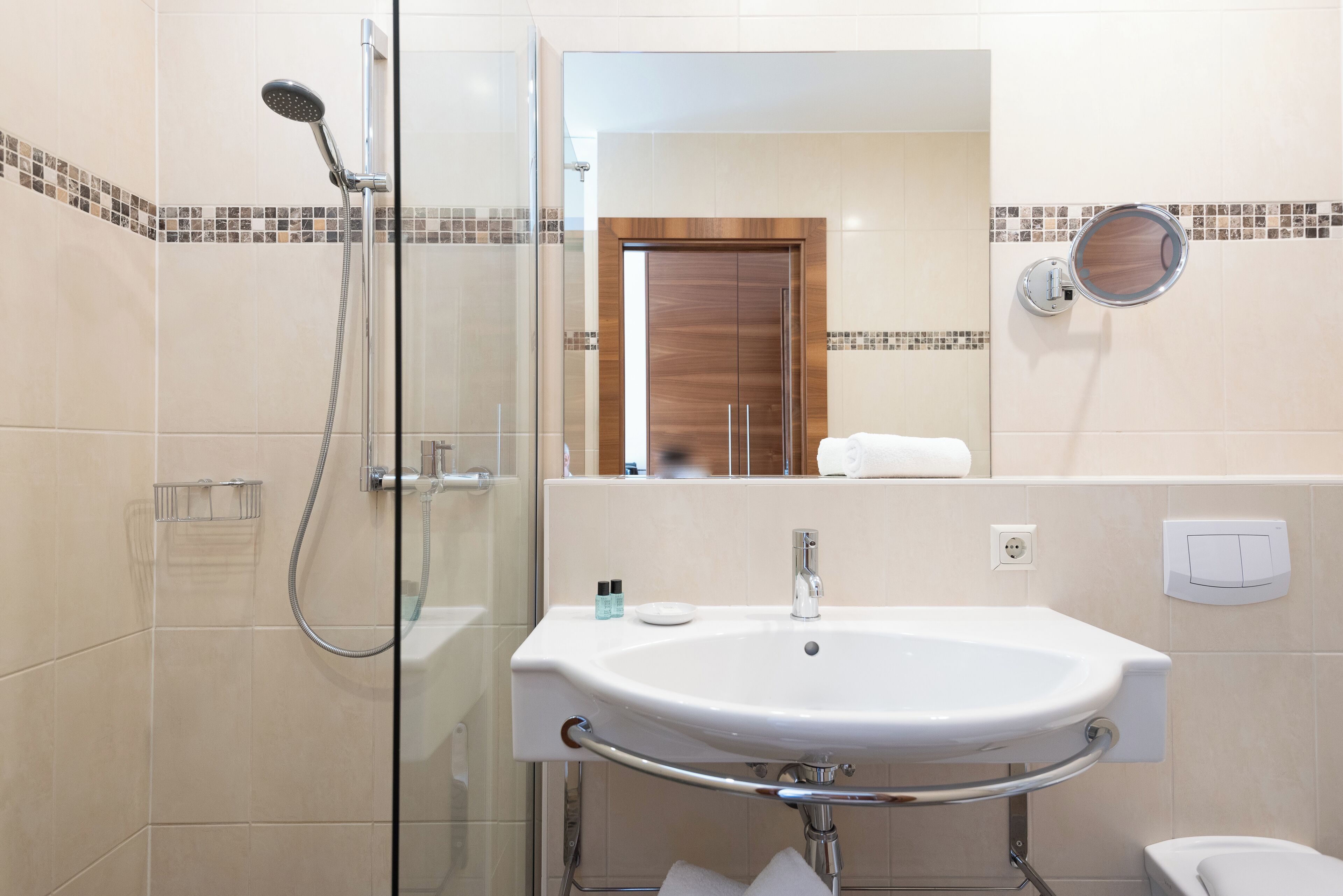 Une salle de bain moderne avec une douche à parois de verre, un lavabo blanc avec un meuble-vasque et un miroir avec un cadre en bois.