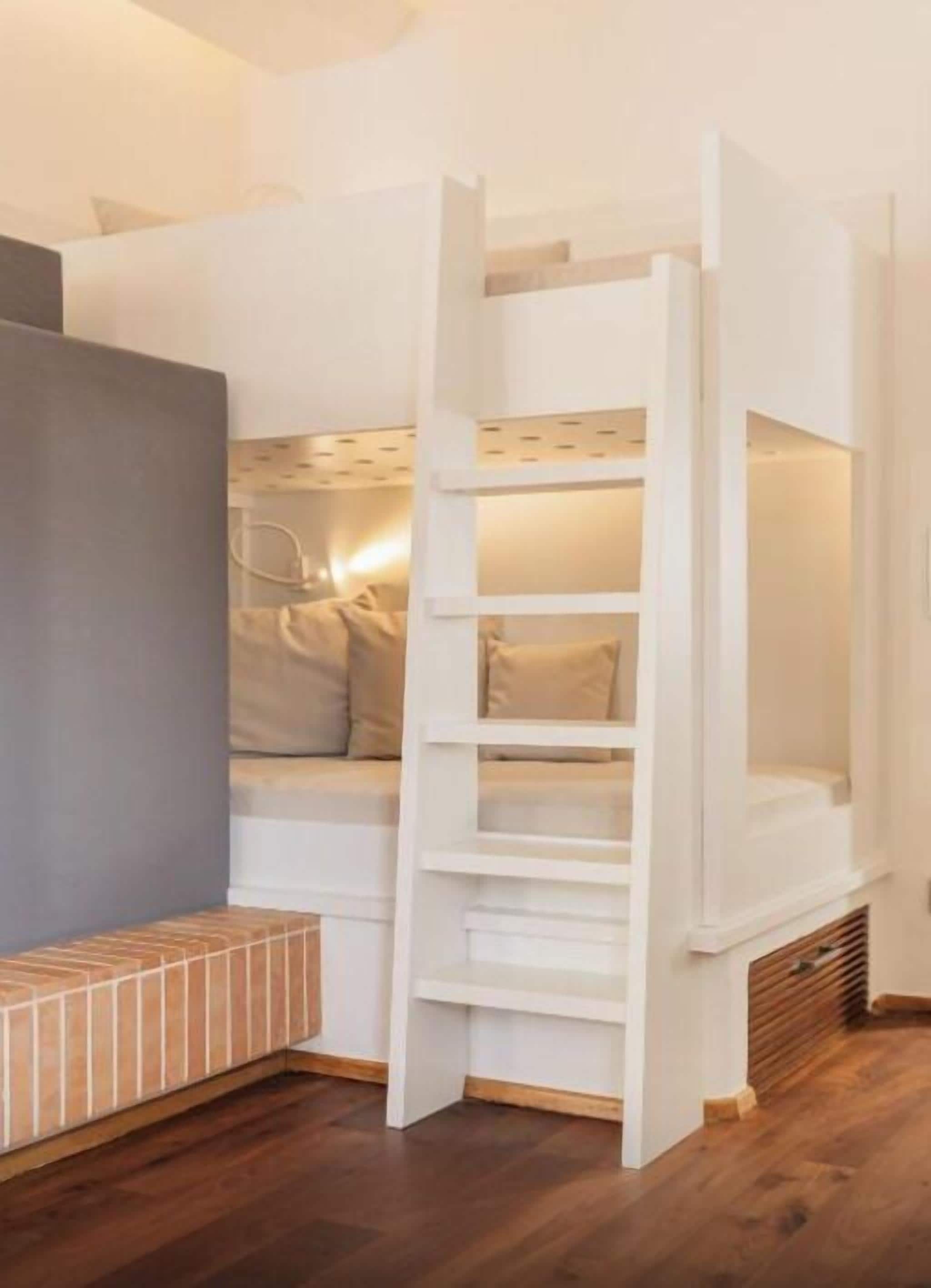 A bunk bed with a ladder, a bench, and a small table.