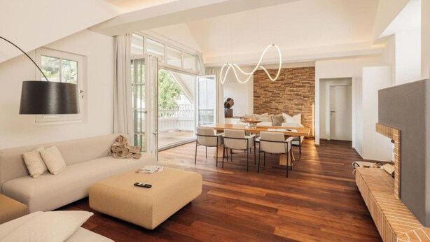 A modern living room with a sofa, ottoman, and a dining area with a table and chairs. - das zellersee (Zell am See)