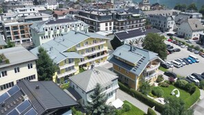 A residential area with multi-story buildings, a parking lot, and a lake in the background. - das zellersee (Zell am See)