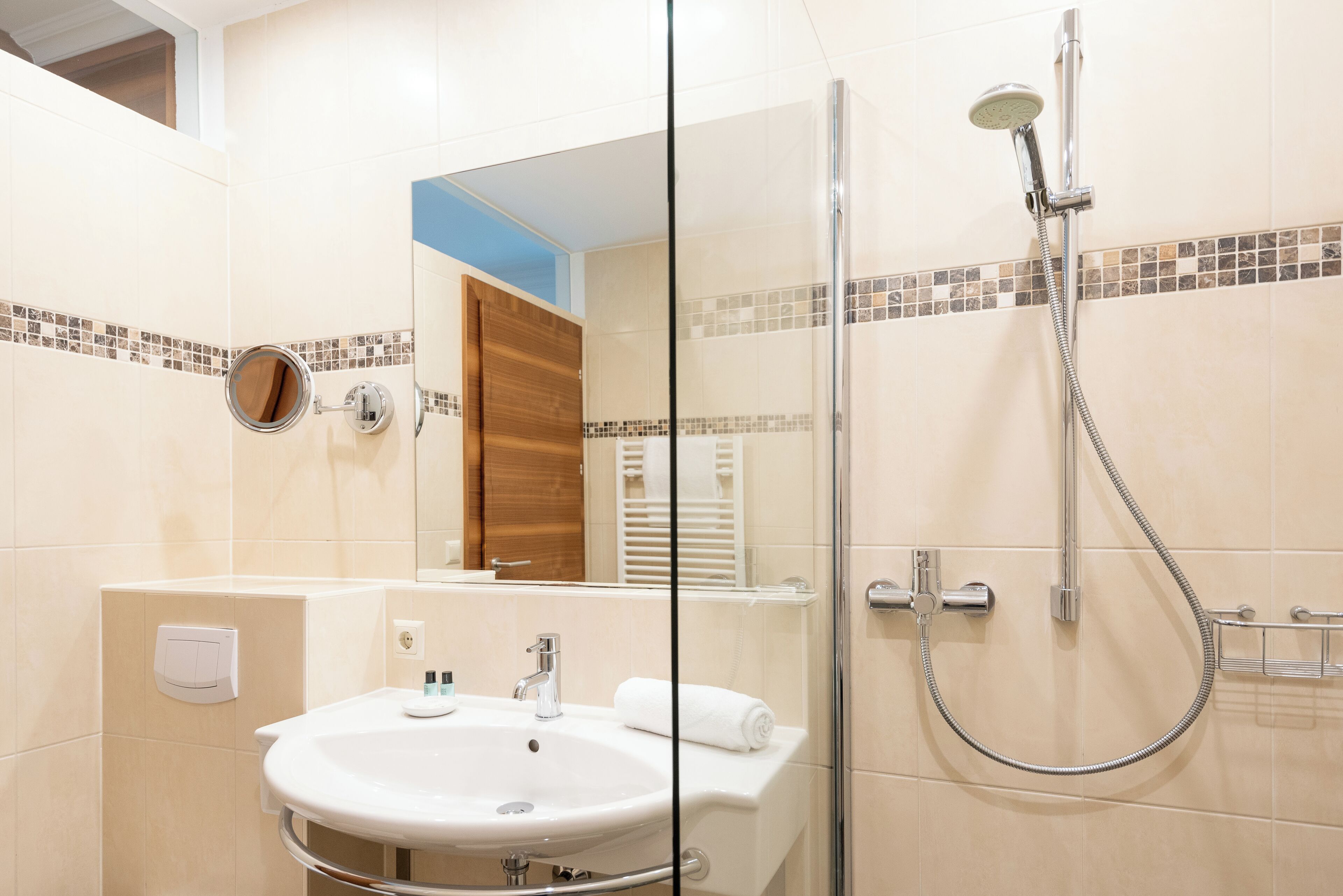 A modern bathroom with a glass-enclosed shower, a white sink, and a mirror.