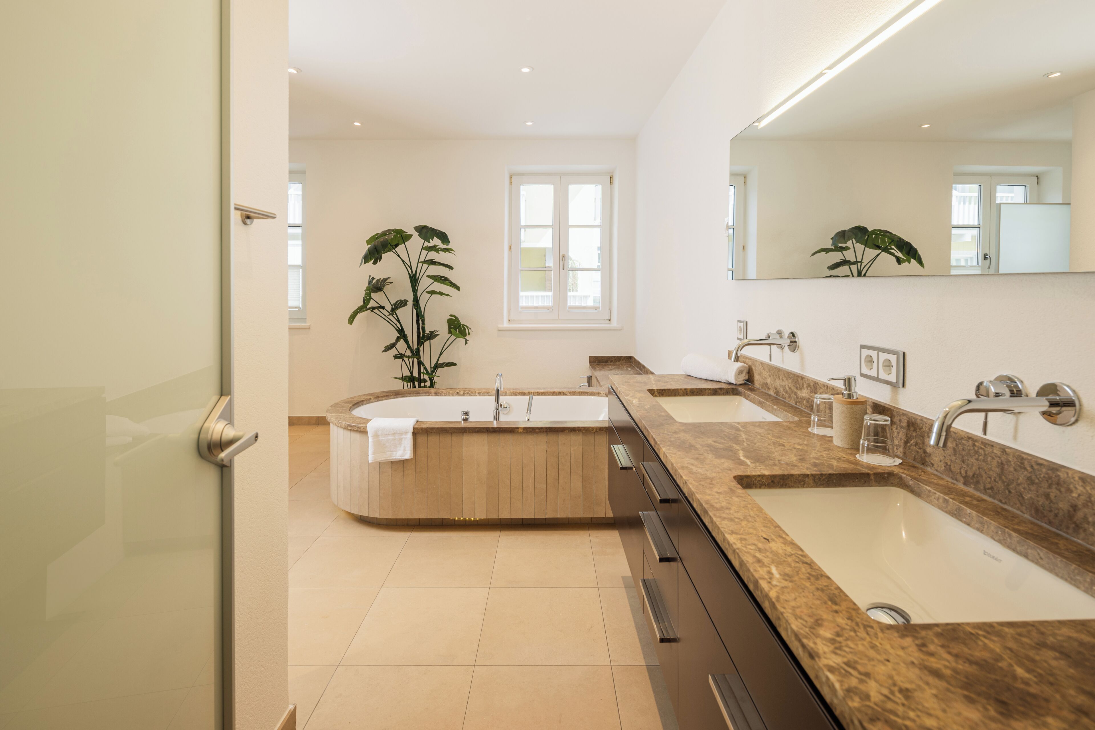 Une salle de bain moderne avec une baignoire sur pieds, un grand miroir et un lavabo double.