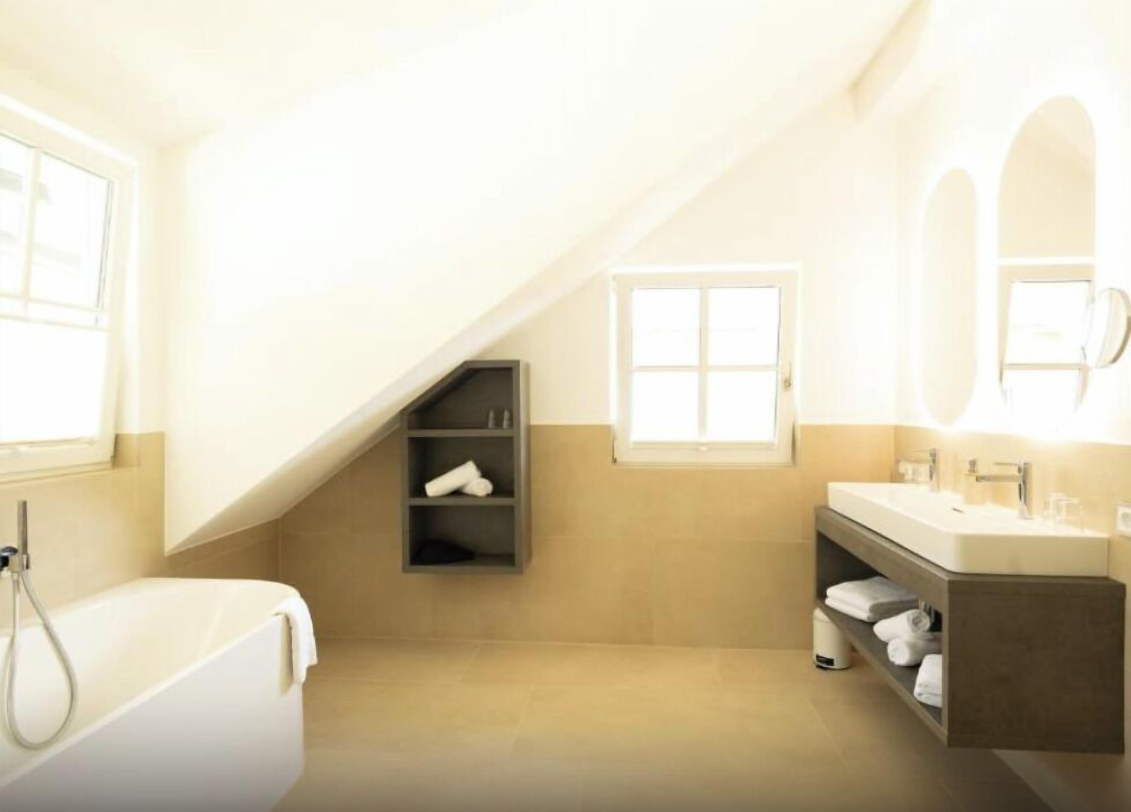 A modern bathroom with a bathtub, a vanity with a mirror, and a shelf with towels.