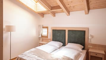 Un dormitorio con techo de madera, una cama con ropa blanca, una mesita de noche y una lámpara de pie.