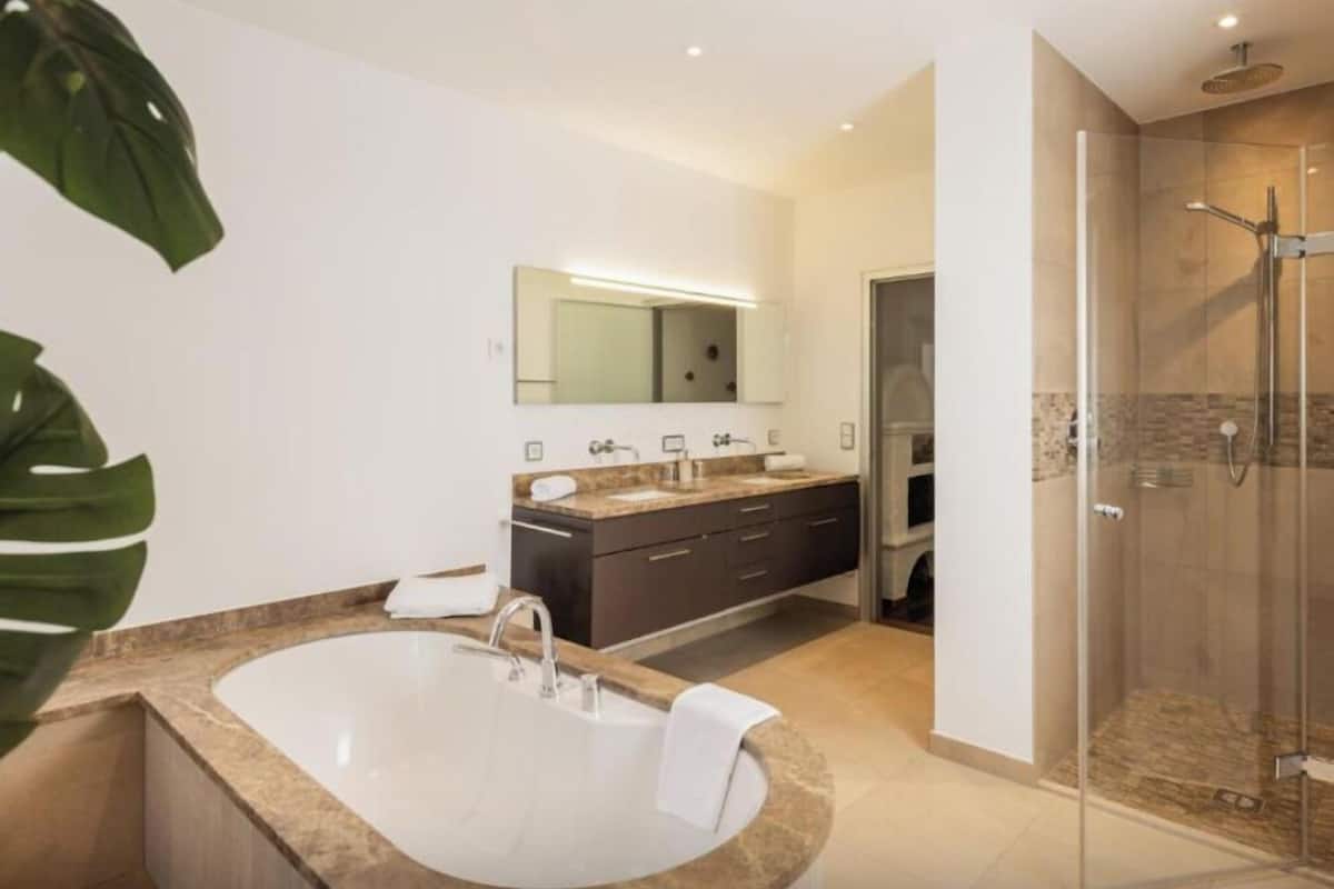 A modern bathroom with a freestanding bathtub, a glass-enclosed shower, and a large mirror above the vanity.
