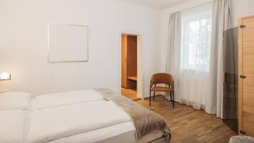 A bedroom with a bed, a chair, a wardrobe, and a door.