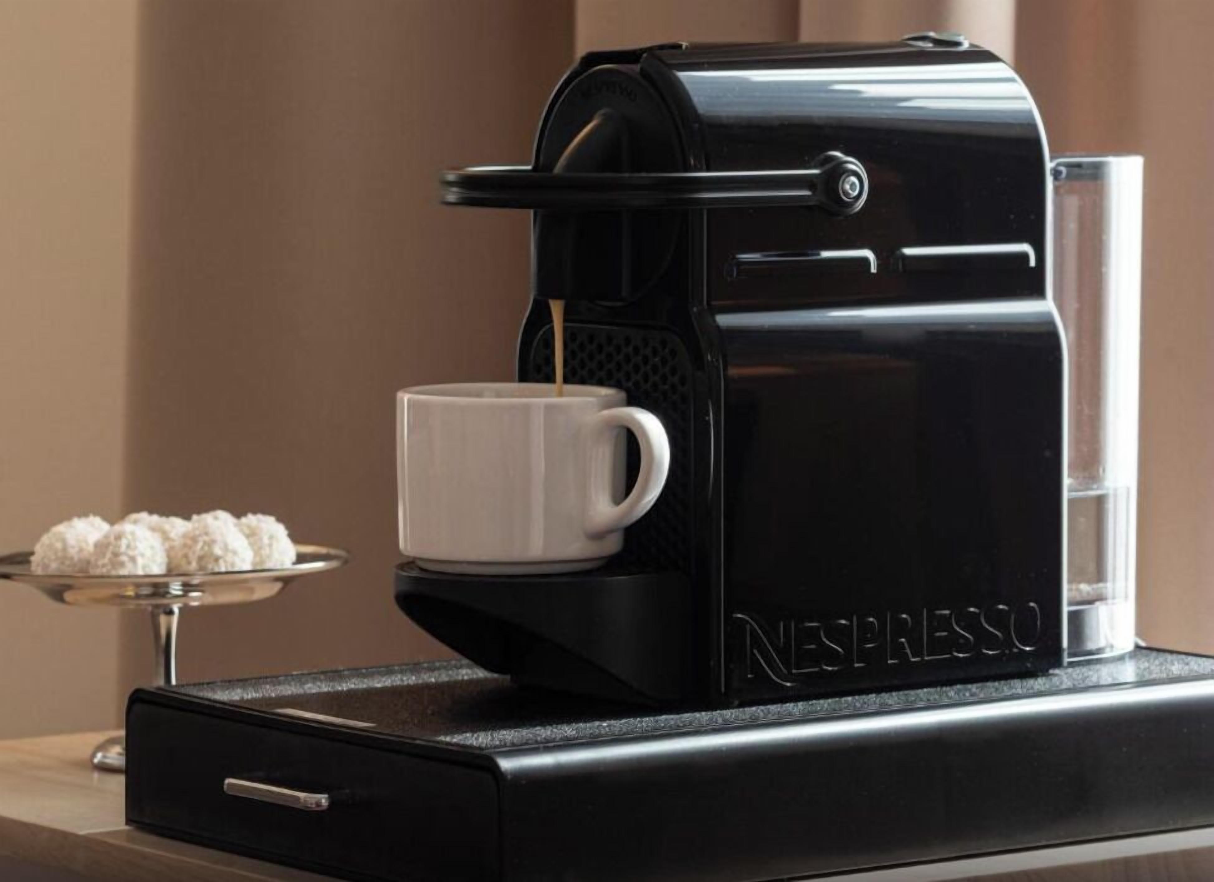 Une machine à café Nespresso, une tasse de café et une assiette de biscuits.