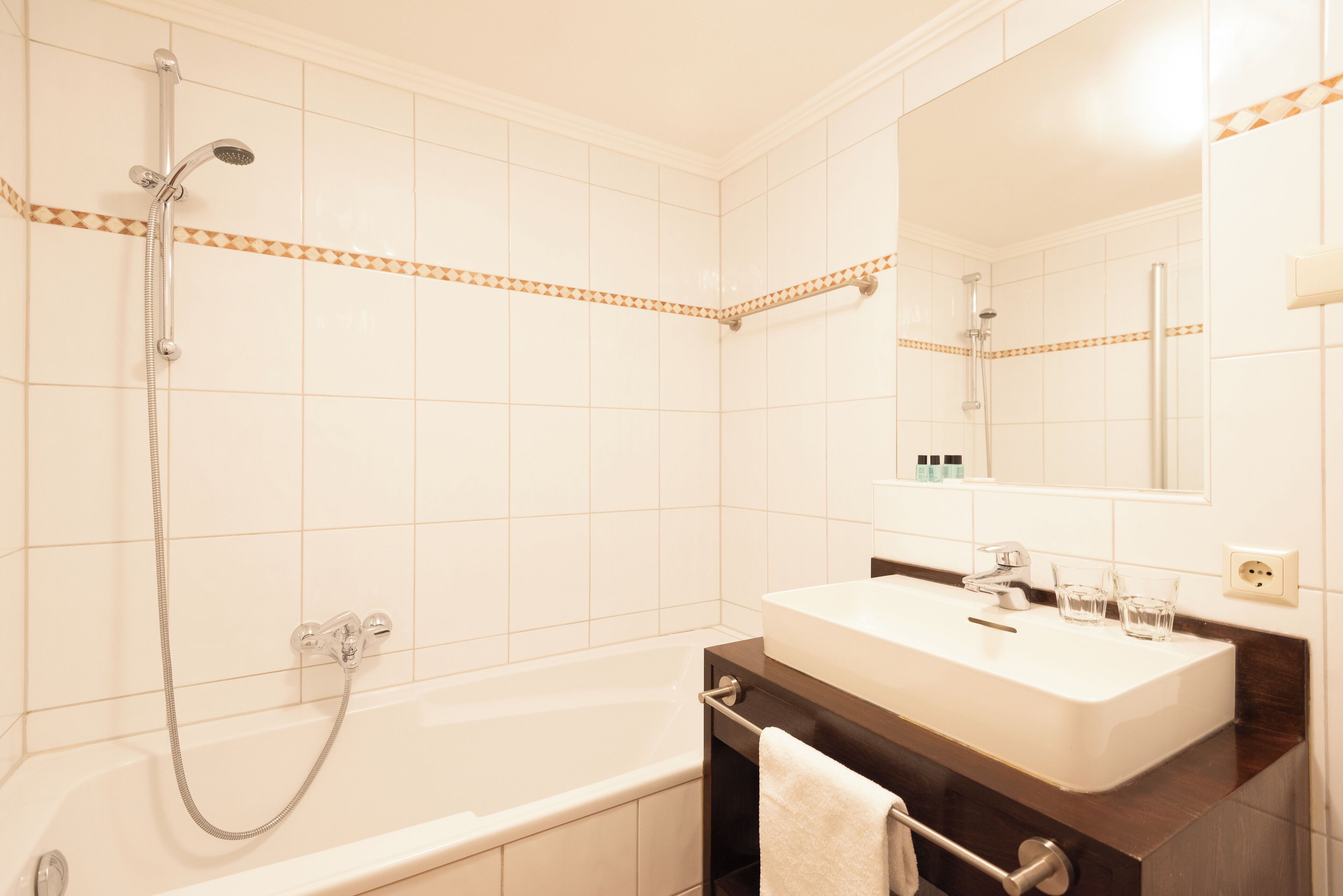 A bathroom with a bathtub, a shower, a sink, and a mirror.