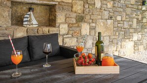 Eine Steinsäule, ein Holztisch, eine schwarze Couch und eine Ablage mit Früchten und Getränken.