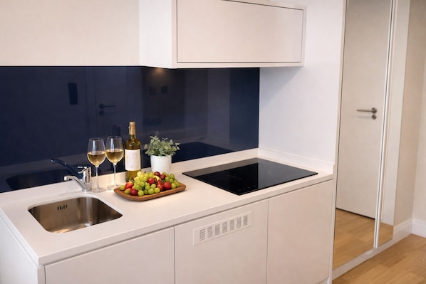 A modern kitchen with a built-in stove, a sink, and a small countertop. - Orbi City Sea View (Batumi)