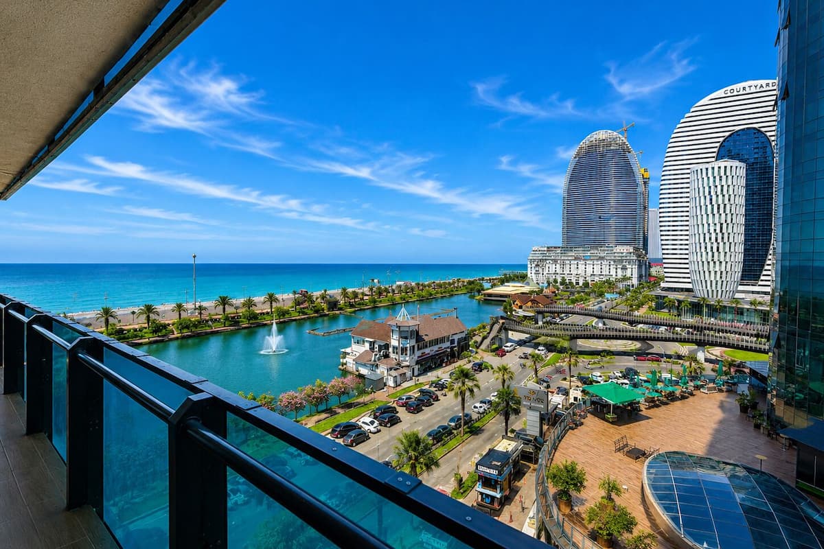 Un paysage urbain côtier avec des bâtiments modernes, une marina et un ciel bleu dégagé.