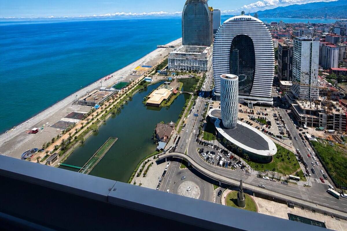 Un paysage urbain côtier avec une architecture moderne, un port de plaisance et un ciel bleu dégagé.