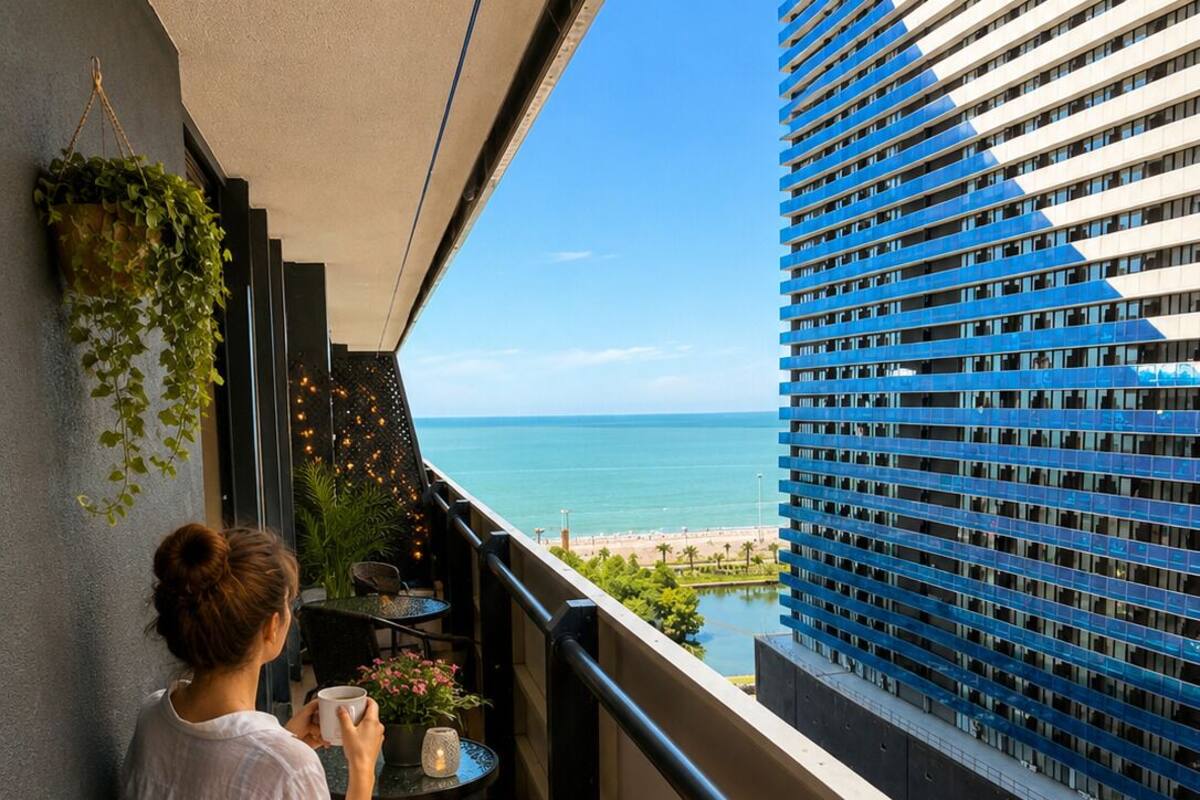 Un balcon avec vue sur la mer, un chien et une personne tenant une tasse.