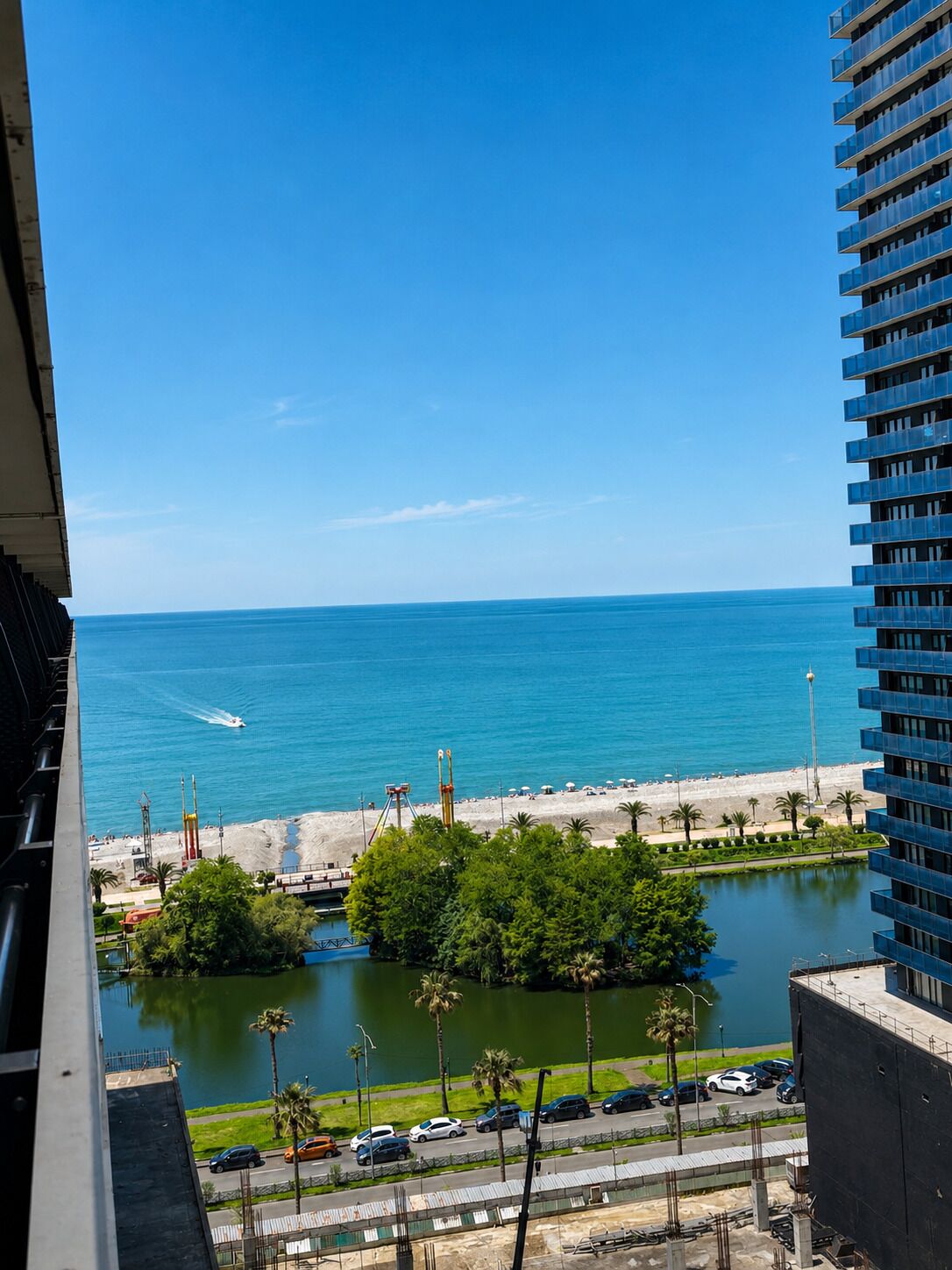 Une vue d’une zone côtière avec une plage, une étendue d’eau et un immeuble de grande hauteur.