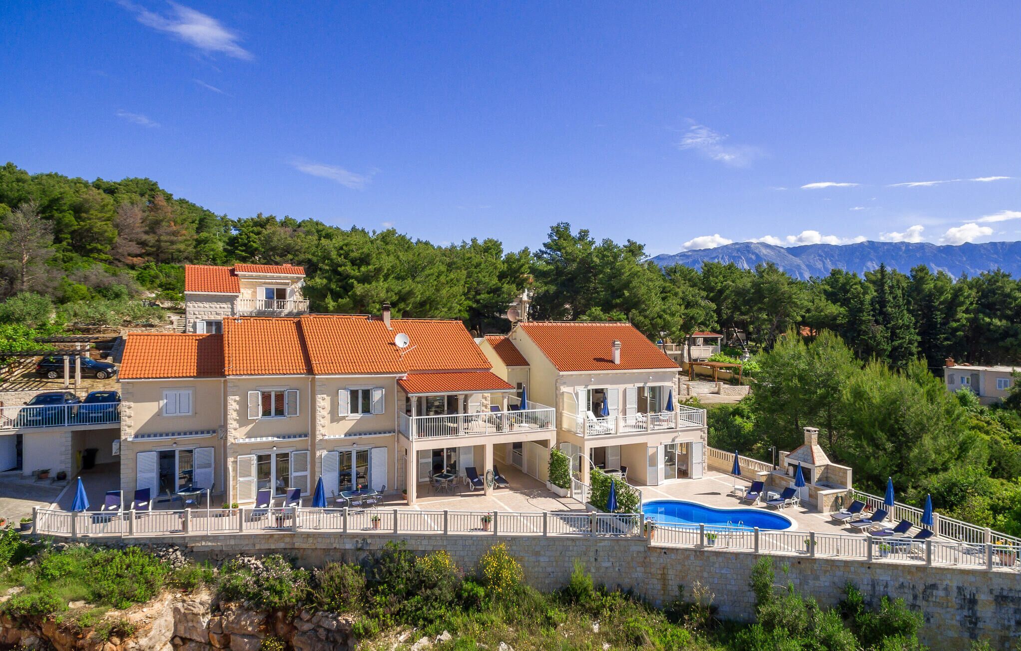 A multi-story building with a swimming pool, outdoor seating, and a view of mountains.